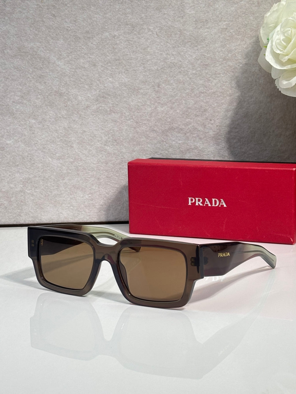 Dark brown sunglasses with brown lenses and Prada logo on temple