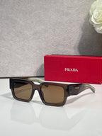 Dark brown sunglasses with brown lenses and Prada logo on temple