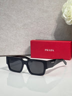 Black sunglasses with dark lenses and Prada logo on temple
