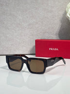 Brown and black sunglasses with dark lenses and Prada logo on temple