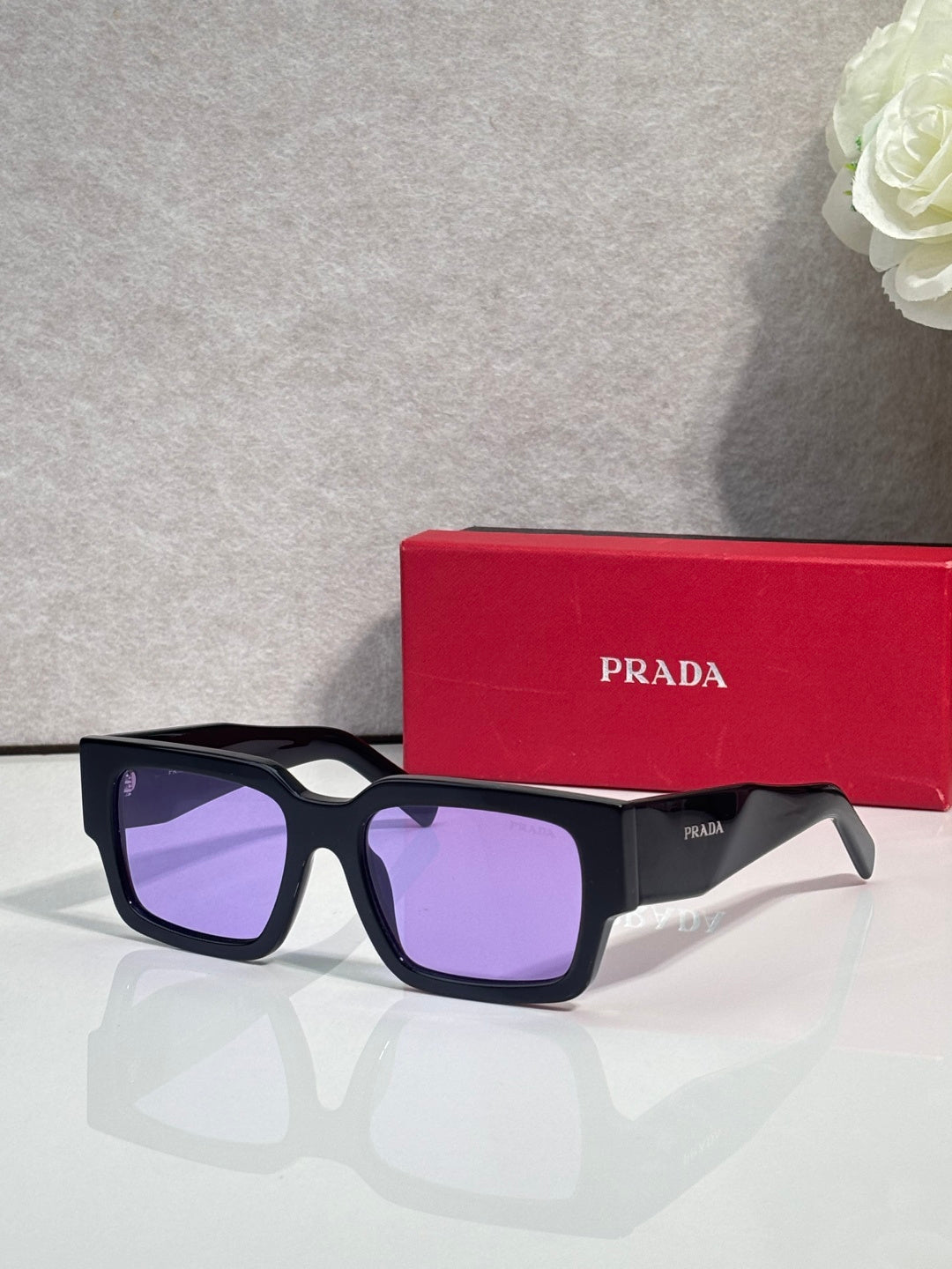 Black sunglasses with purple lenses and Prada logo on temple