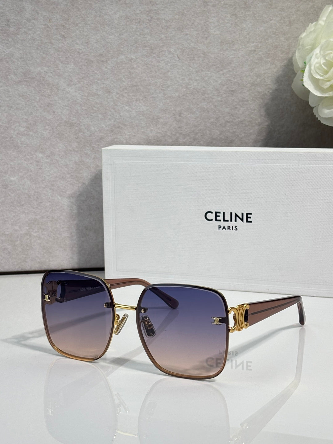 Celine sunglasses with dark blue frames, gold accents, and gradient tinted lenses.