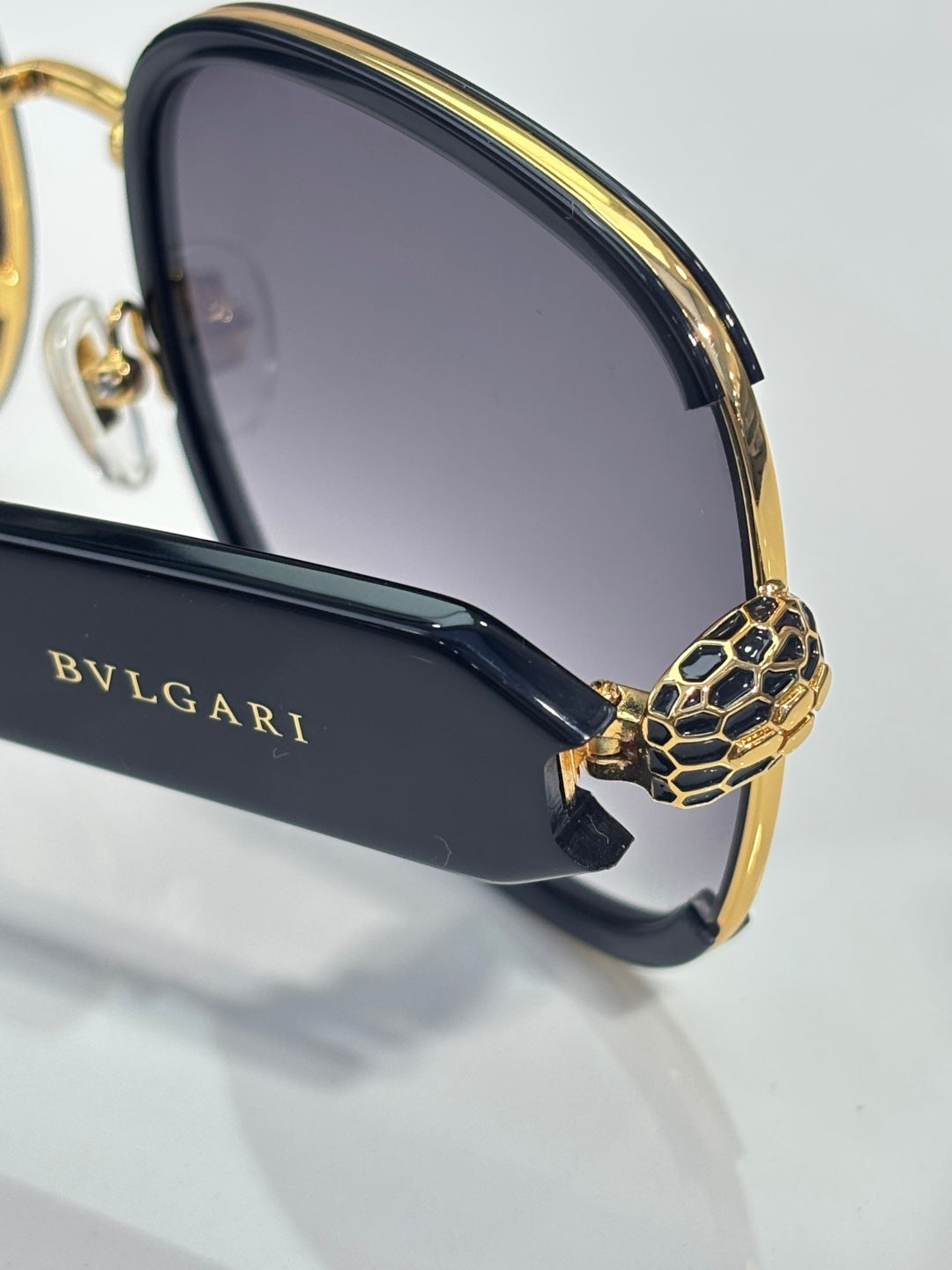 Sunglasses side close-up: gold patterned temple and BVLGARI branding on arm