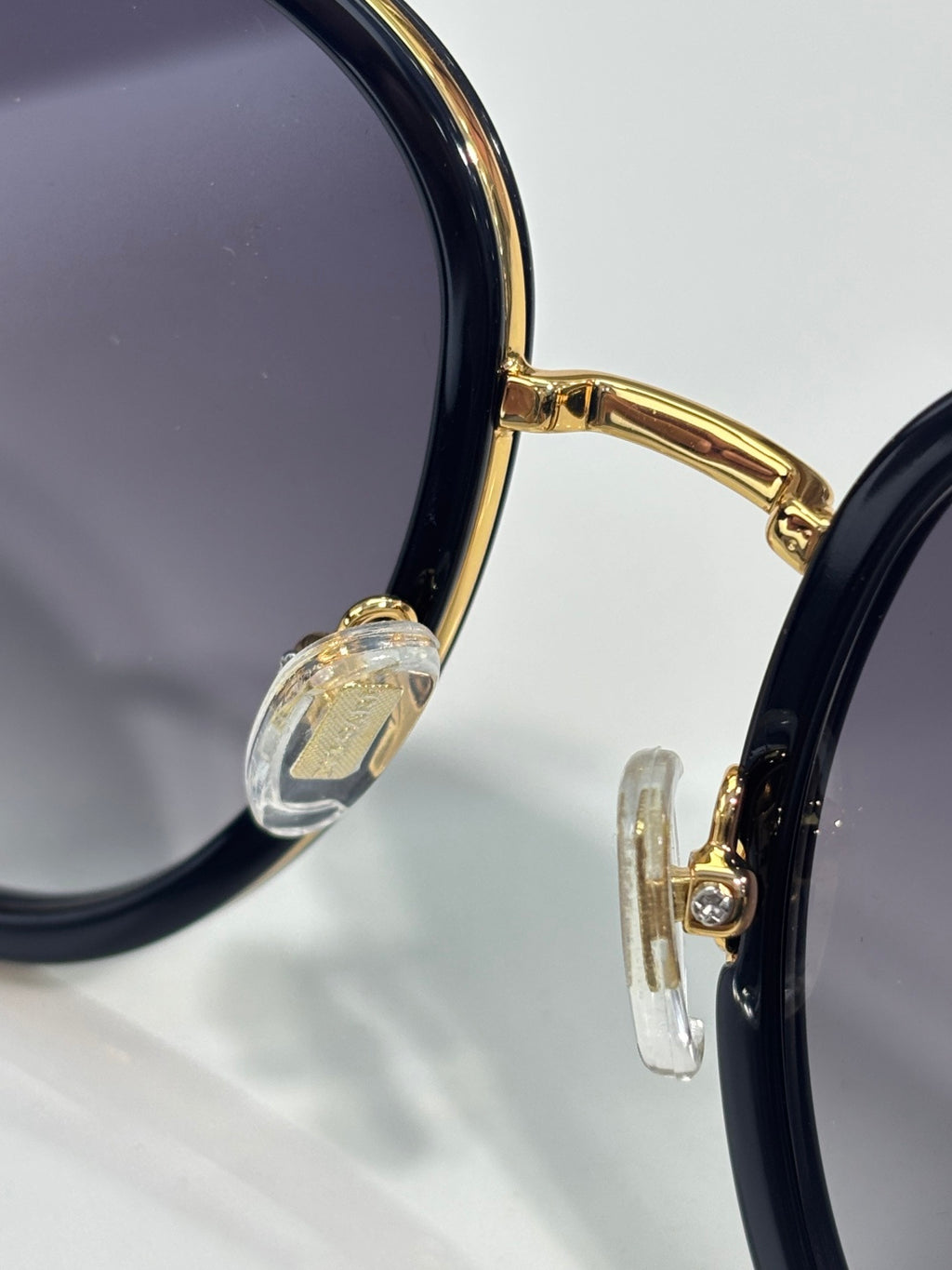 Sunglass frame close-up: gold hinge with clear decorative detail