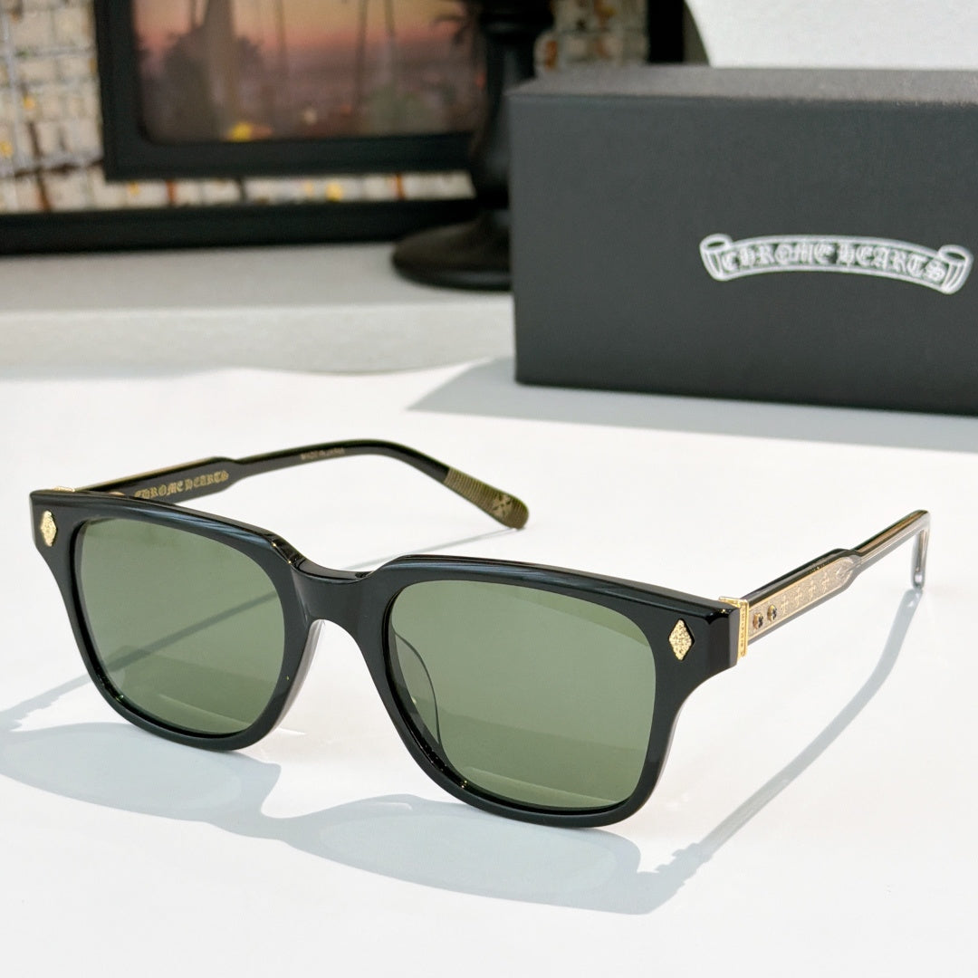Black square sunglasses with green-tinted lenses and gold-tone patterned temple bars