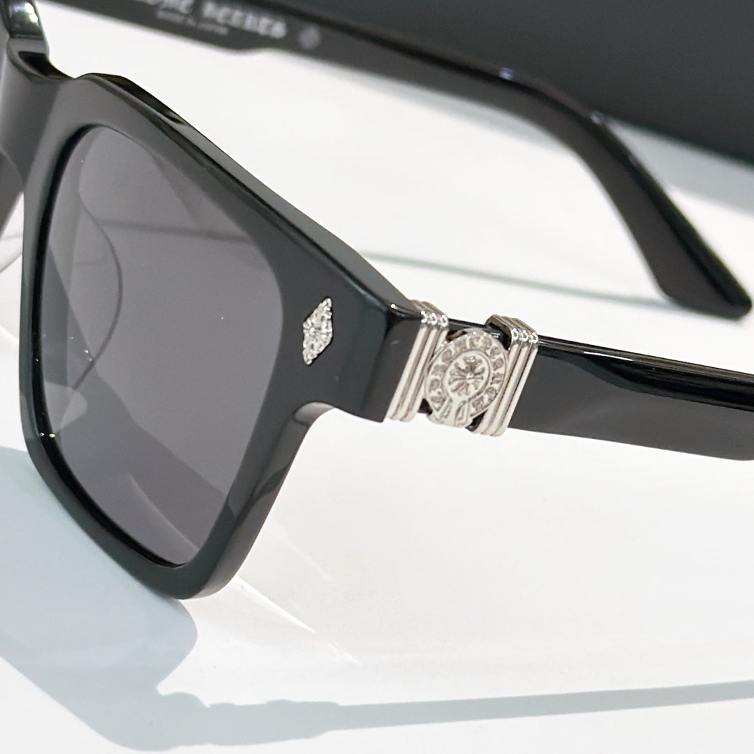 Black square sunglasses close-up: rhinestone emblem and silver hinge