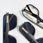 Prada black sunglasses close-up, dark lenses with gold logo hinges on temples