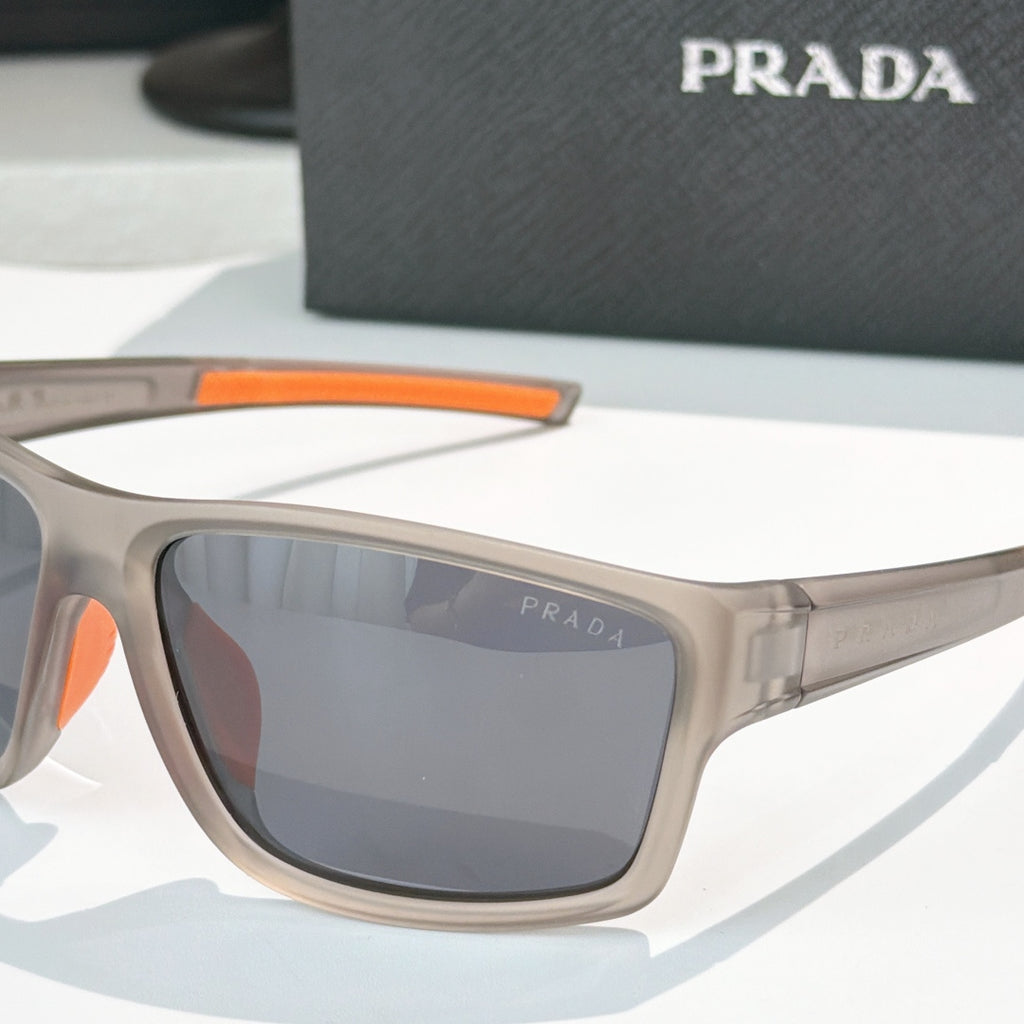 Prada sunglasses close-up: beige frame with orange detail and dark tinted lens