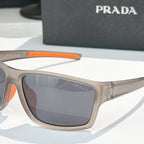 Prada sunglasses close-up: beige frame with orange detail and dark tinted lens