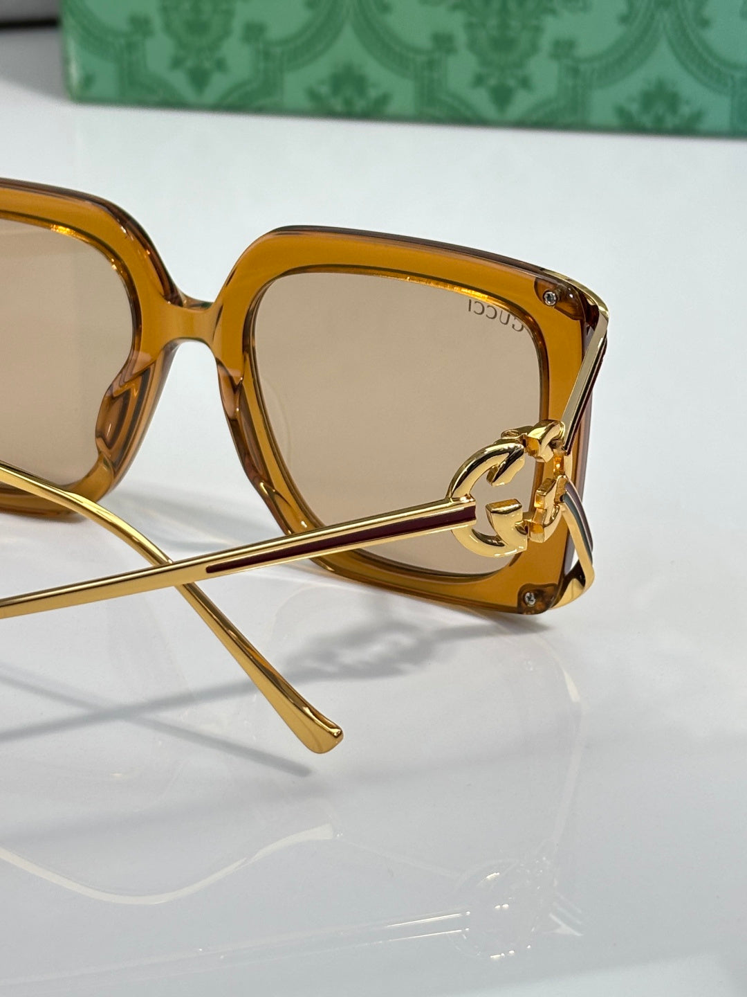Gucci sunglasses close-up: amber frame and logo hinge on the temple