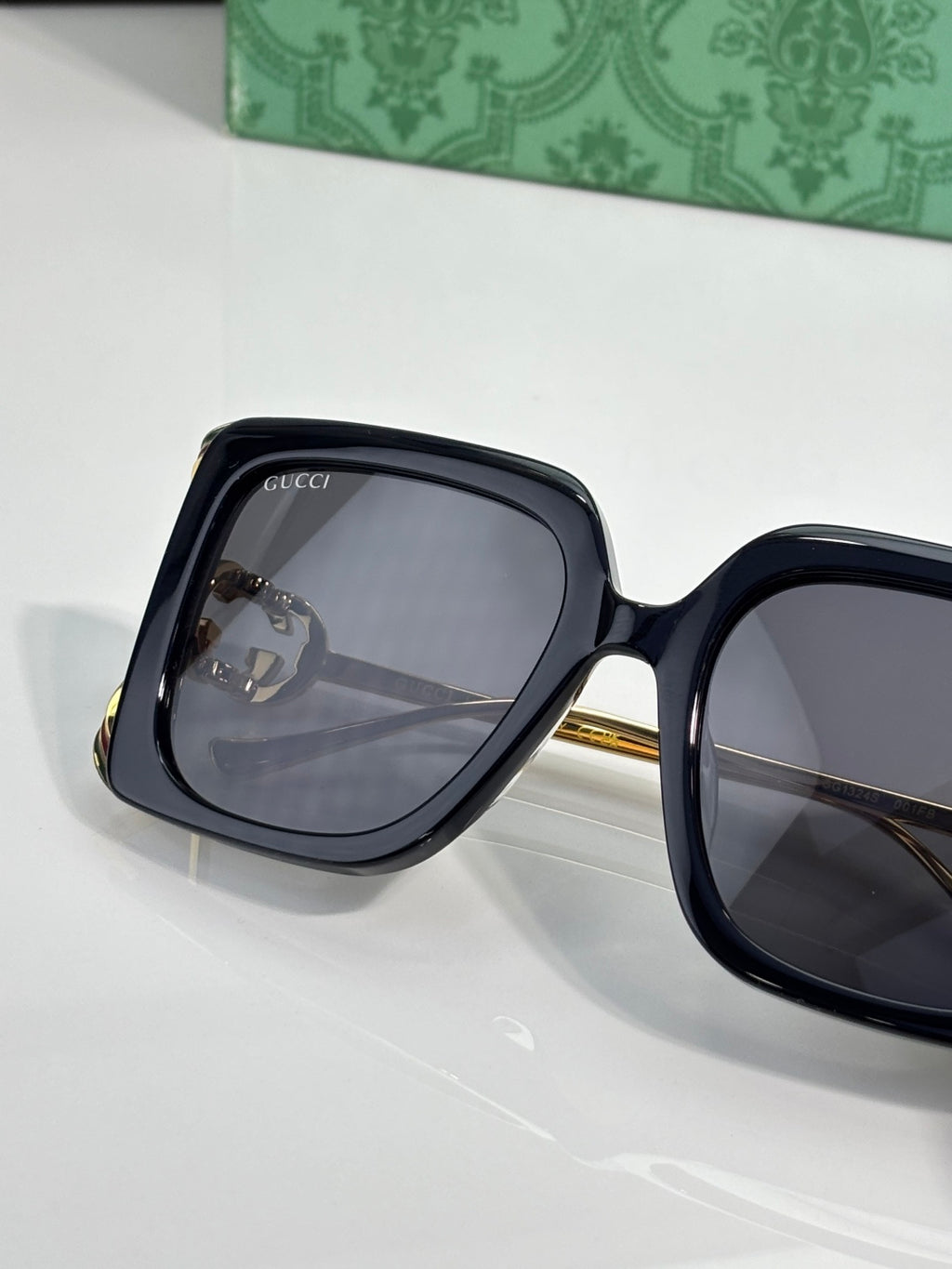 Black oversized sunglasses with dark lenses and gold-tone hinge hardware.