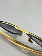 Bottega Veneta sunglasses close-up with gold bar detail and dark lens