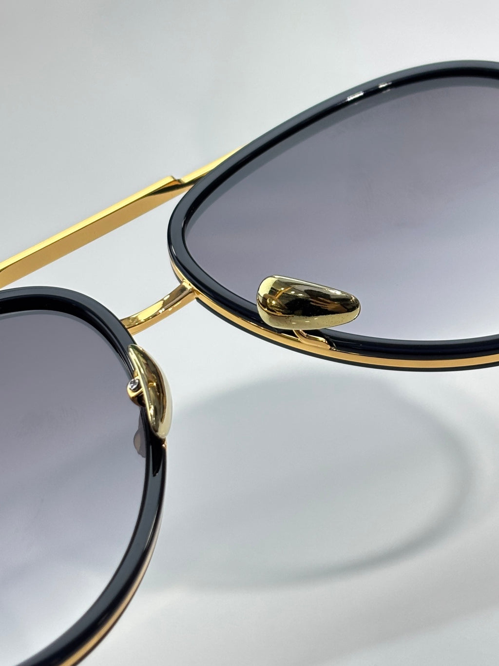 Bottega Veneta sunglasses close-up of gold hinge and dark oval lens