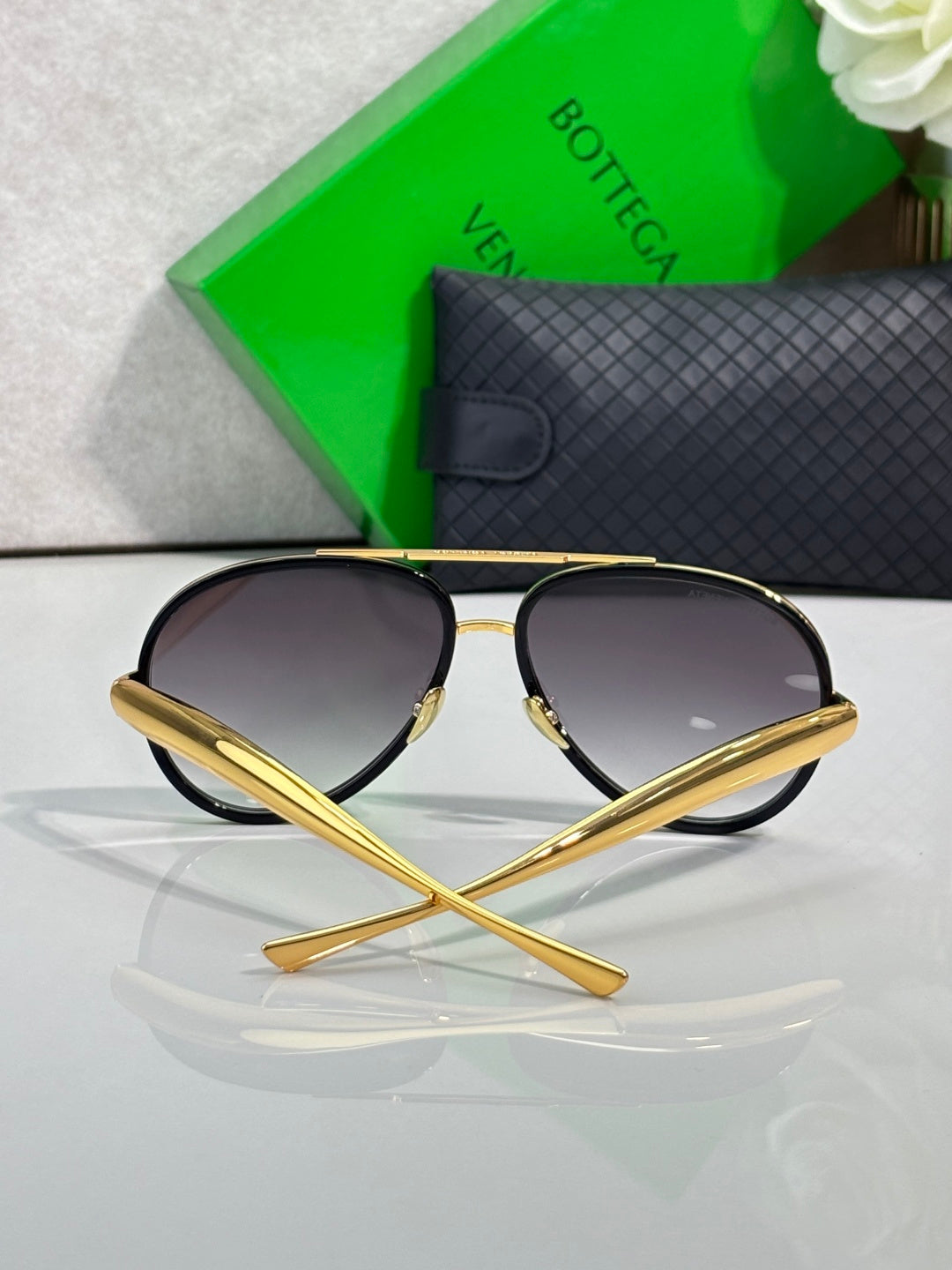 Bottega Veneta sunglasses angled view with dark lenses and gold frame
