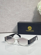 Sunglasses with light silver frame, dark lenses, gold logo detail on temple