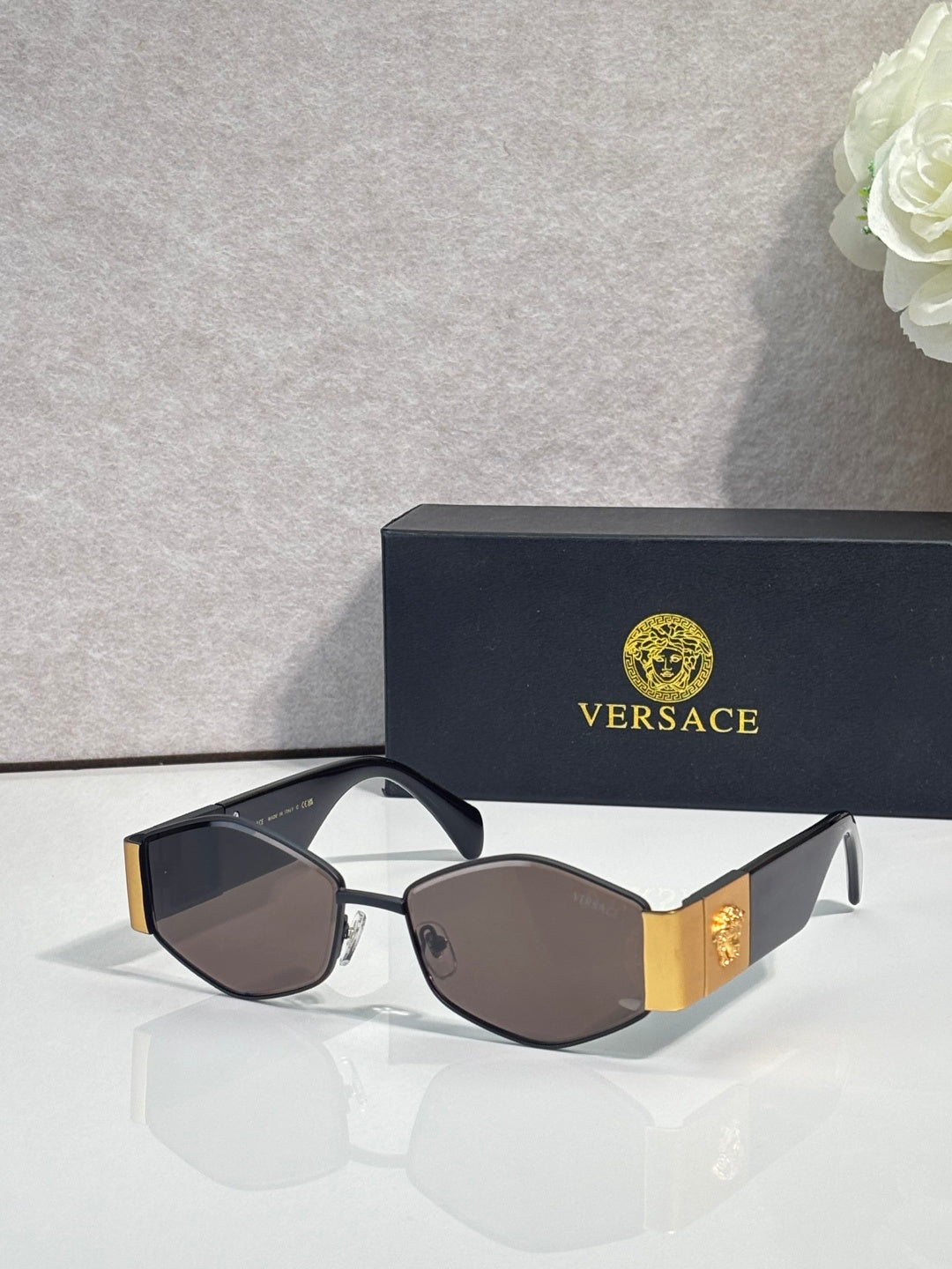 Sunglasses with gold frame, dark brown lenses, black temple with gold logo