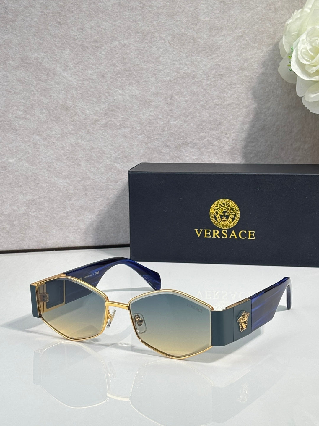 Sunglasses with blue temple accents, dark lenses, gold-tone logo detail
