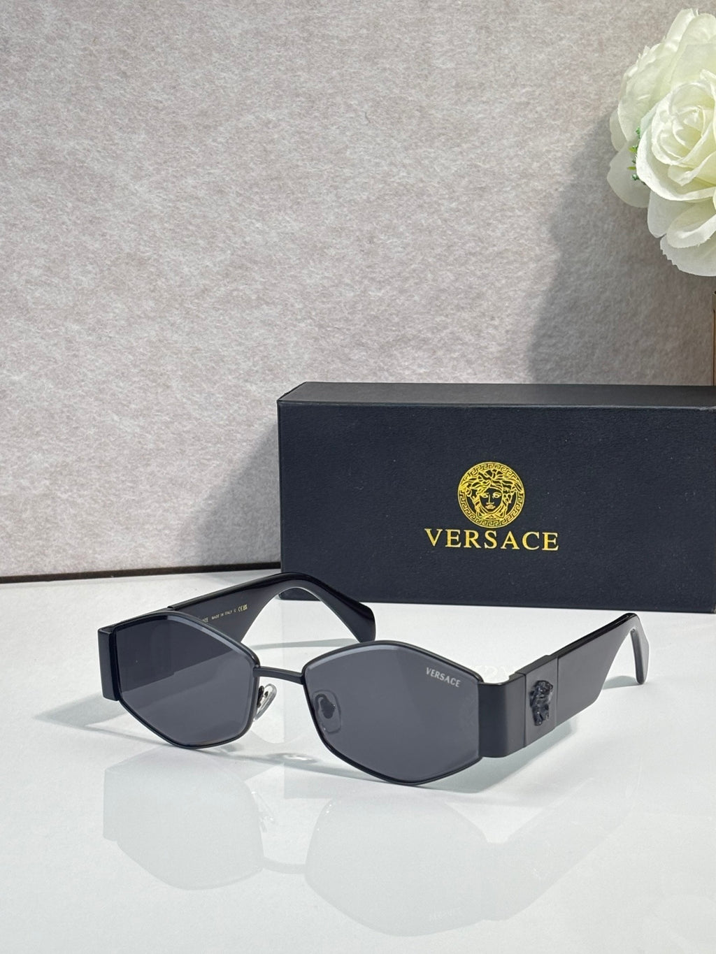 Sunglasses with black frame, dark lenses, gold logo detail on temple