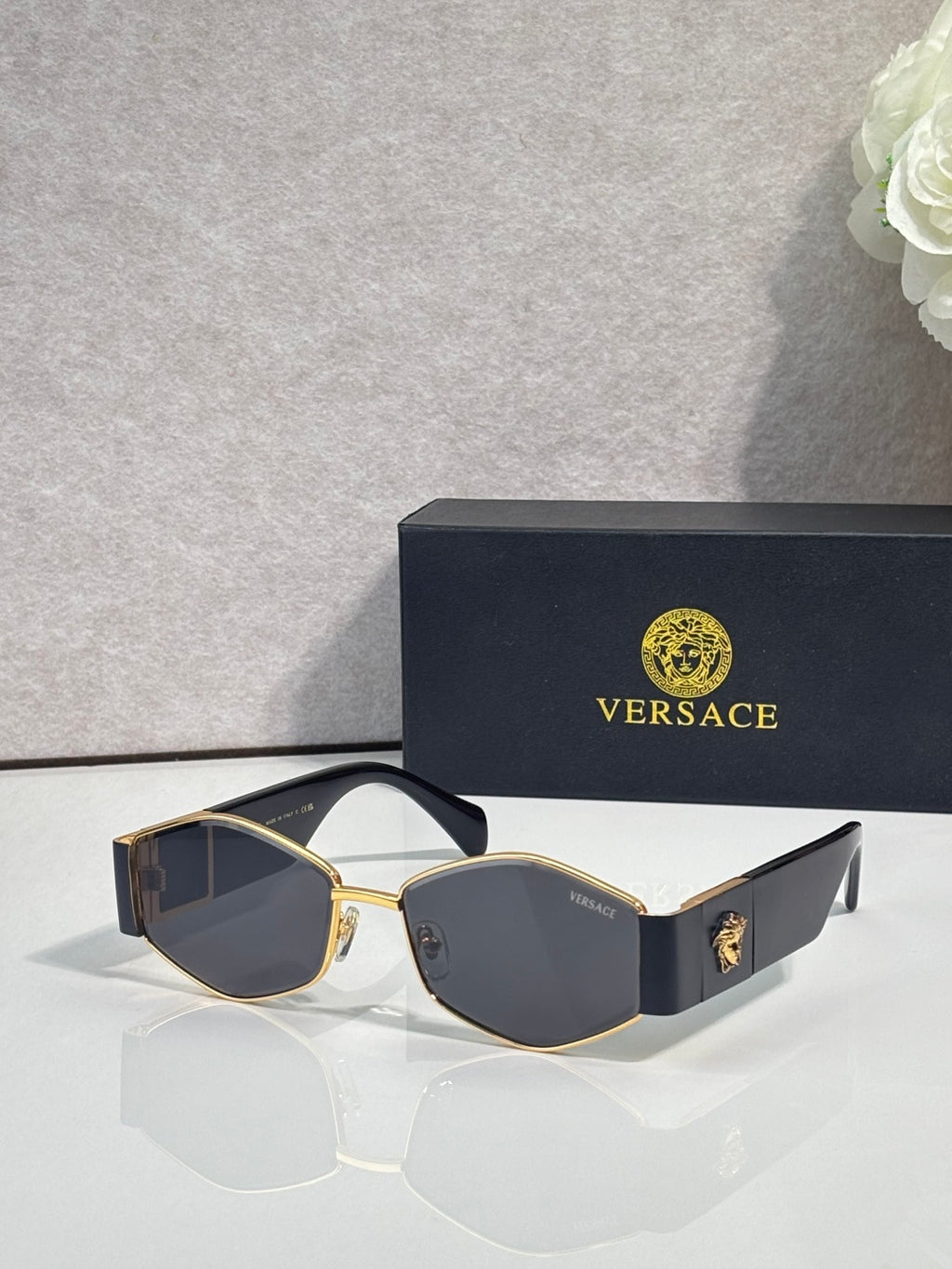 Sunglasses with gold frame, dark lenses, blue temple with gold logo detail