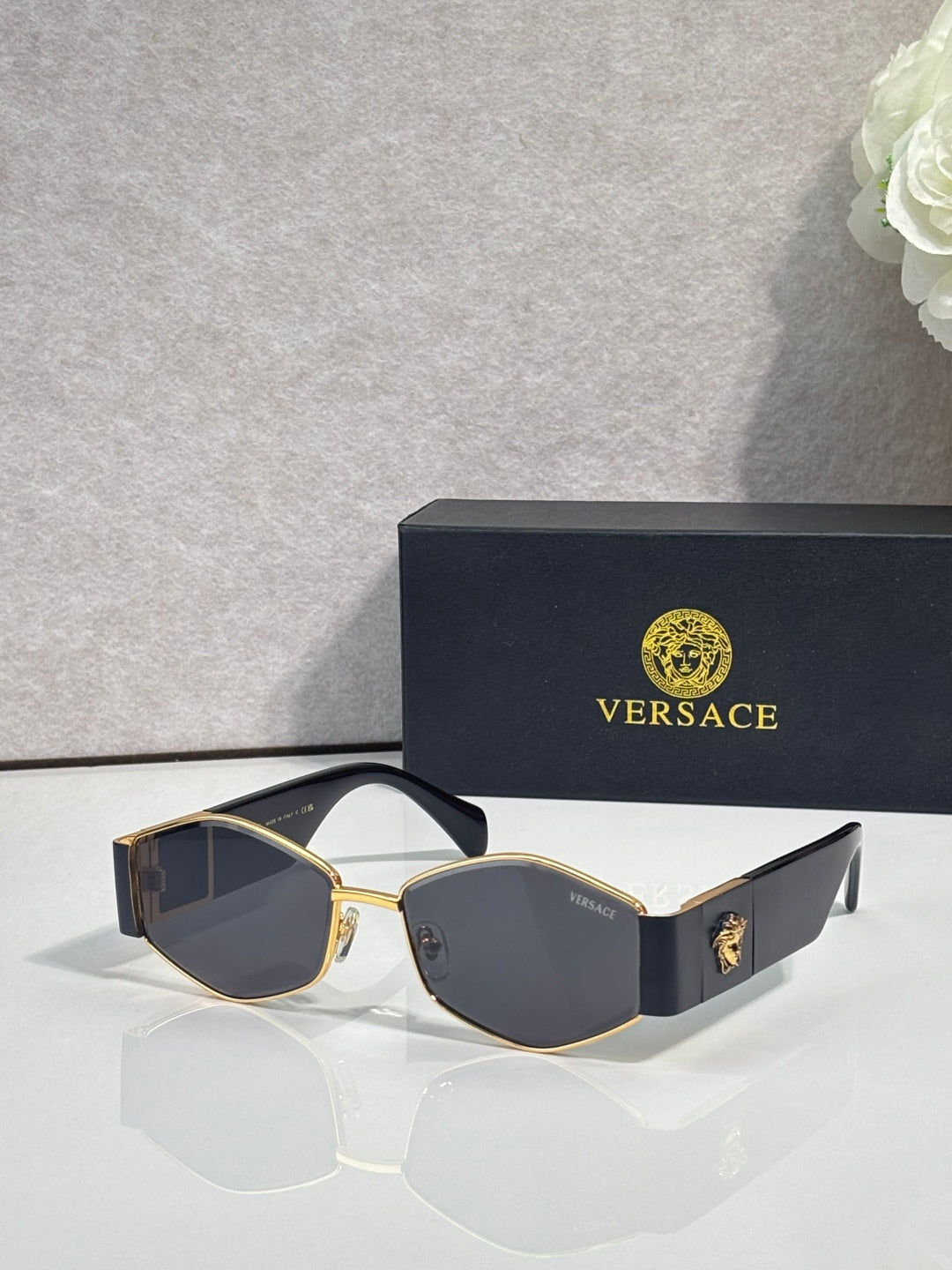 Sunglasses with gold frame, dark lenses, blue temple with gold logo detail