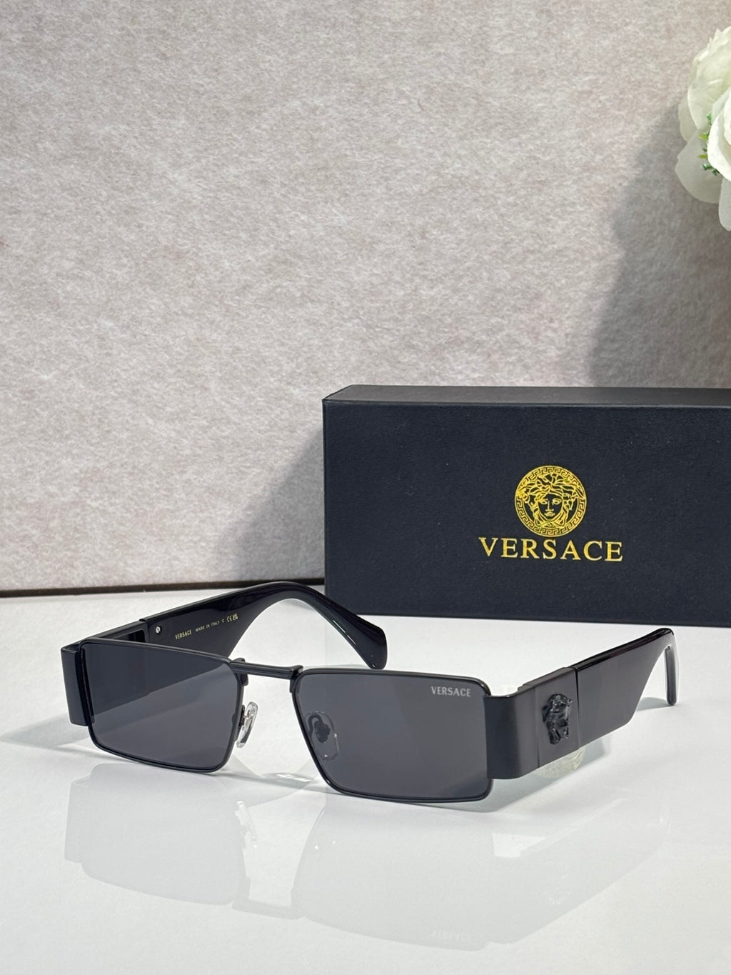Versace angular sunglasses with dark lenses, dark frame, and gold-tone logo accents
