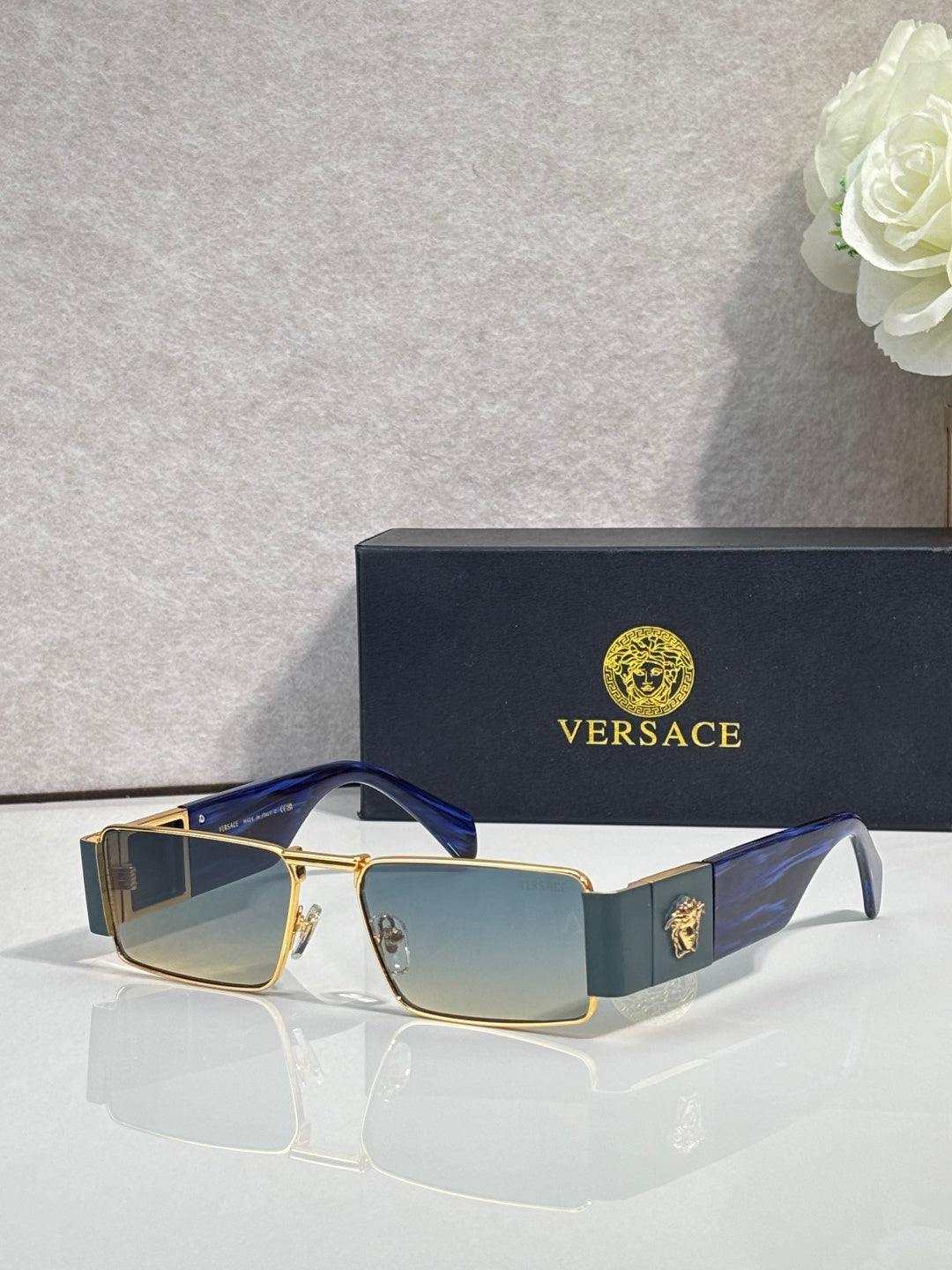 Versace rectangular sunglasses with gold-tone frame and dark blue lenses, black temple tips