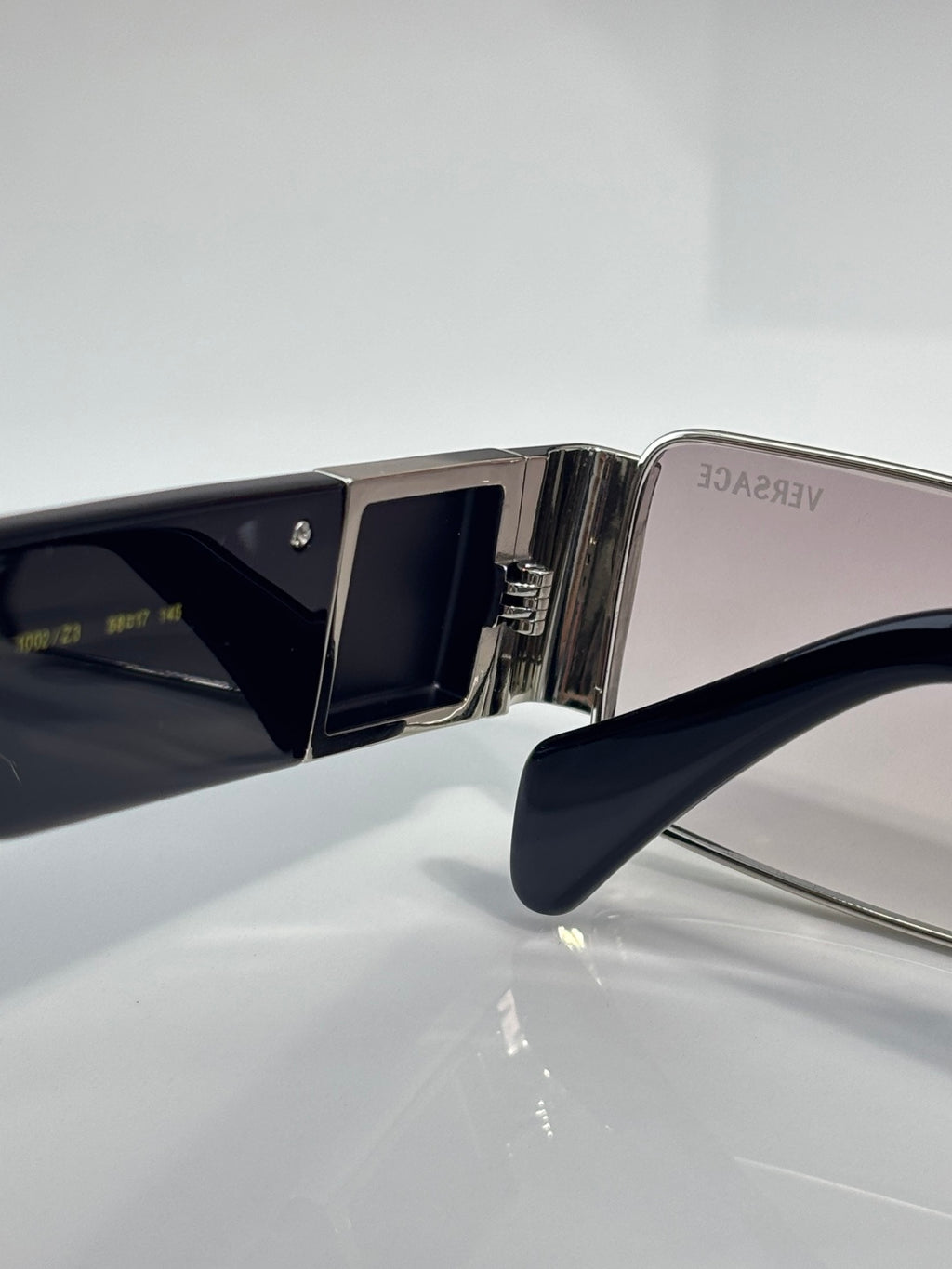 Versace sunglasses temple and lens close-up, silver metal with dark blue frame