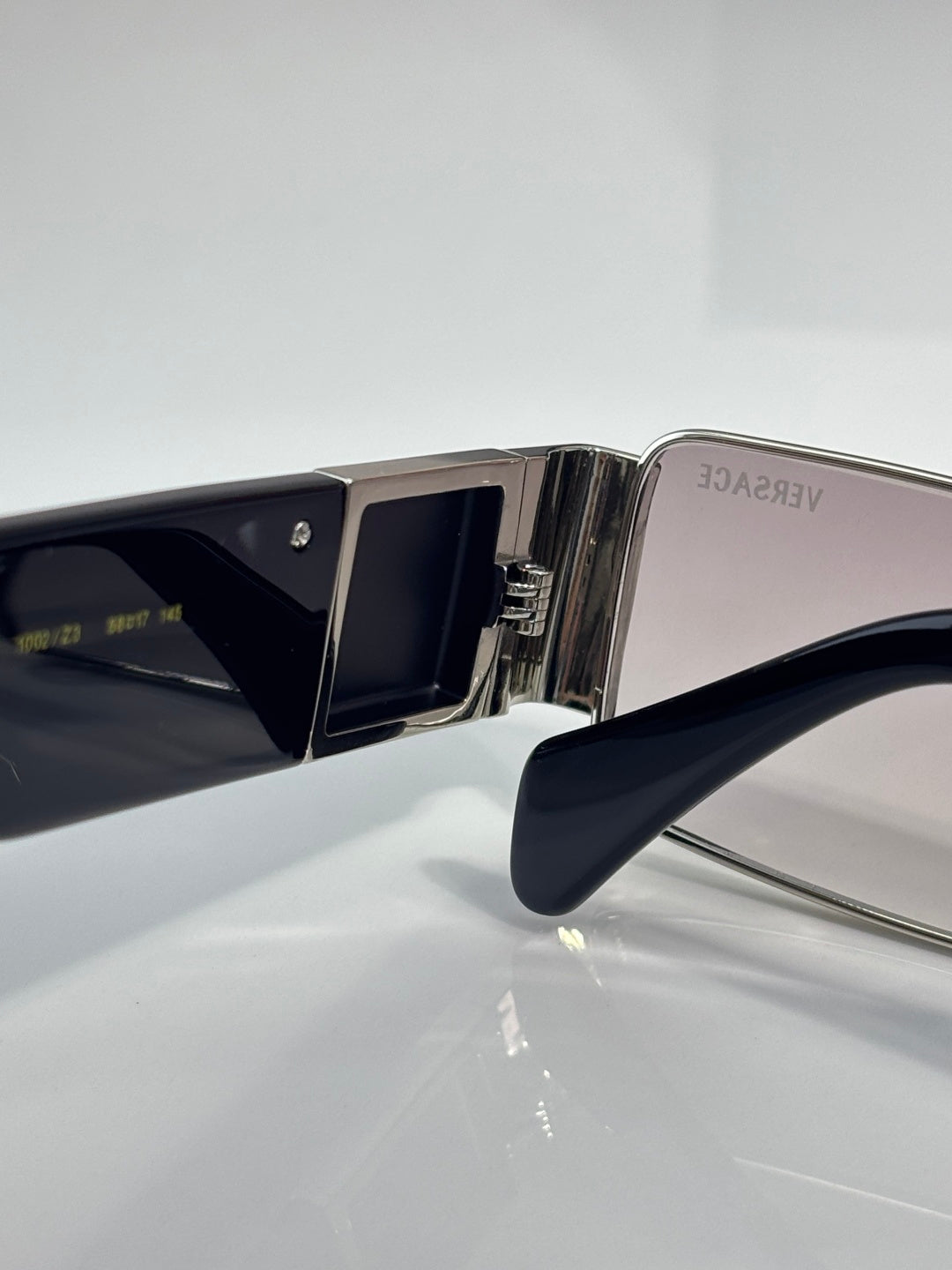 Versace sunglasses temple and lens close-up, silver metal with dark blue frame