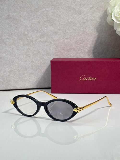 Black oval glasses with gold temples, dark lenses, and metal detailing on arm