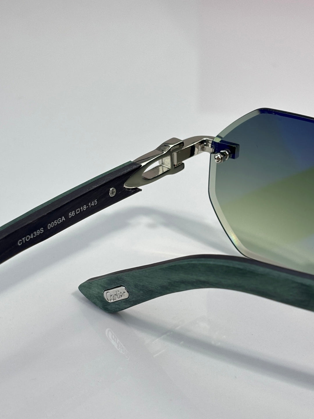 Cartier round eyeglasses with green temples, silver metal frame, and engraved arms