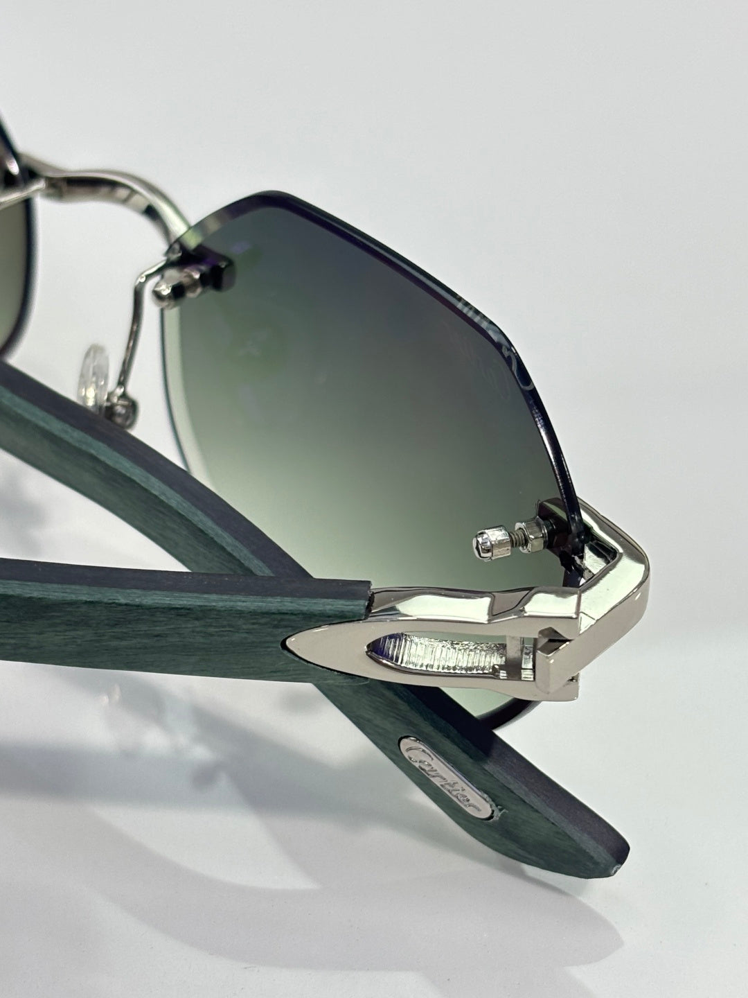 Cartier glasses close-up: dark lenses, silver frame, green temple, metal hinge