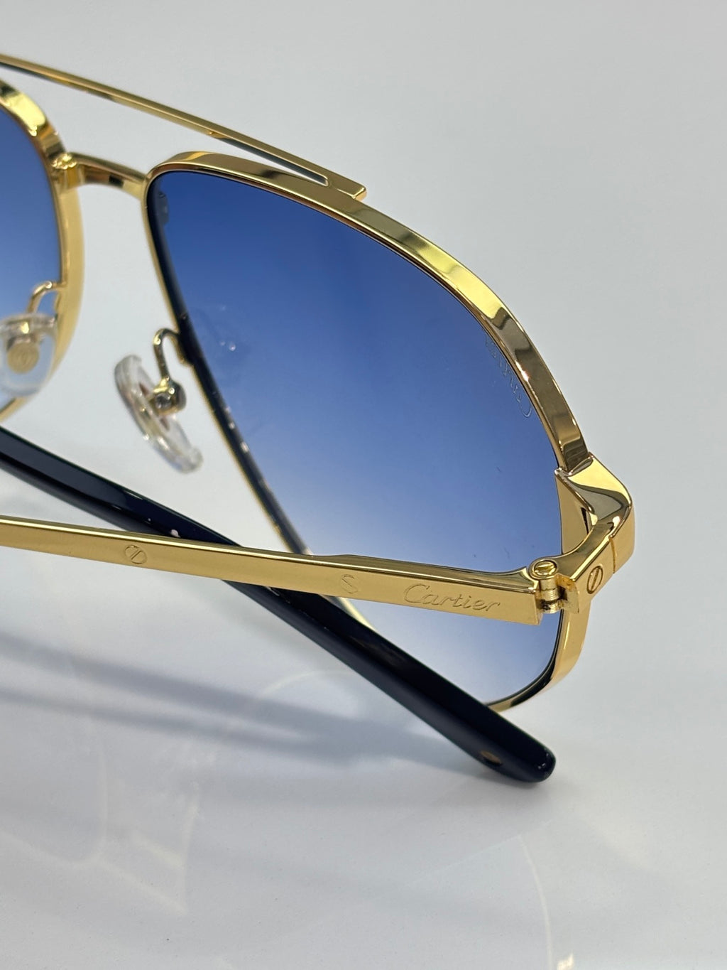 Close-up metal sunglasses with blue lens and gold temple arms