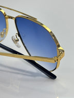 Close-up metal sunglasses with blue lens and gold temple arms