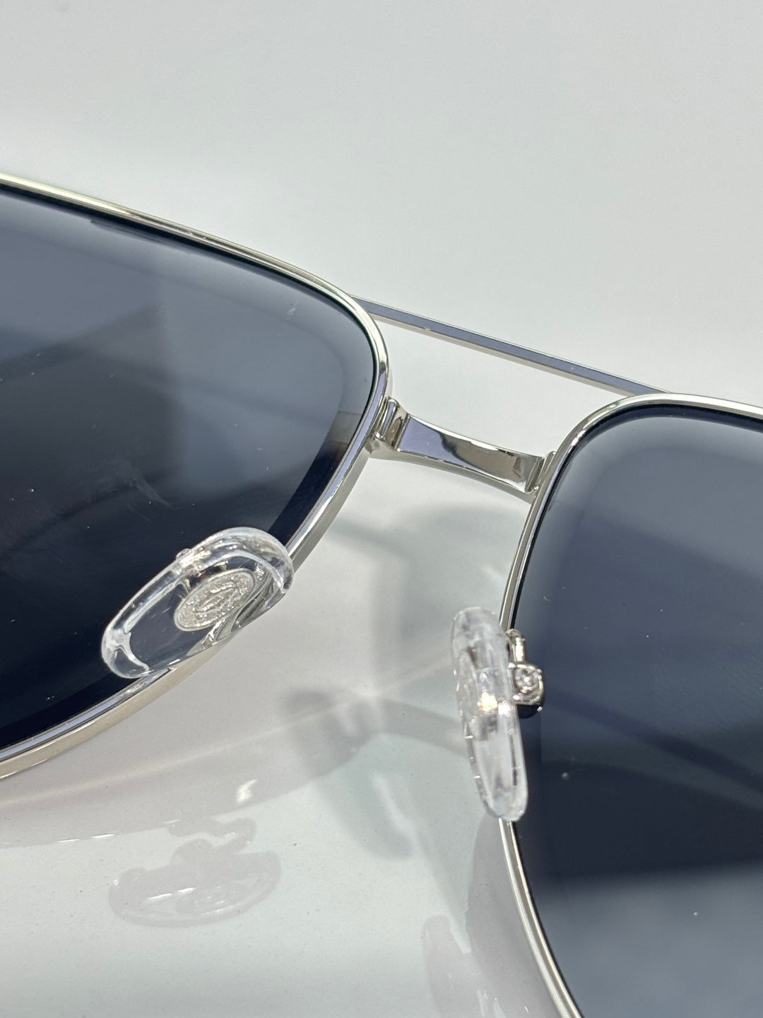 Cartier sunglasses close-up: silver frame, dark lens, bridge and hinge detail