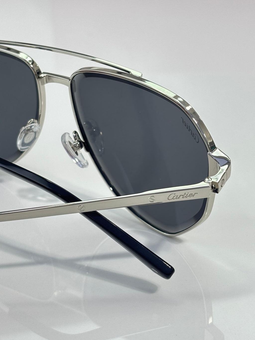 Cartier sunglasses angled view, silver frame with dark lenses and Cartier logo temple
