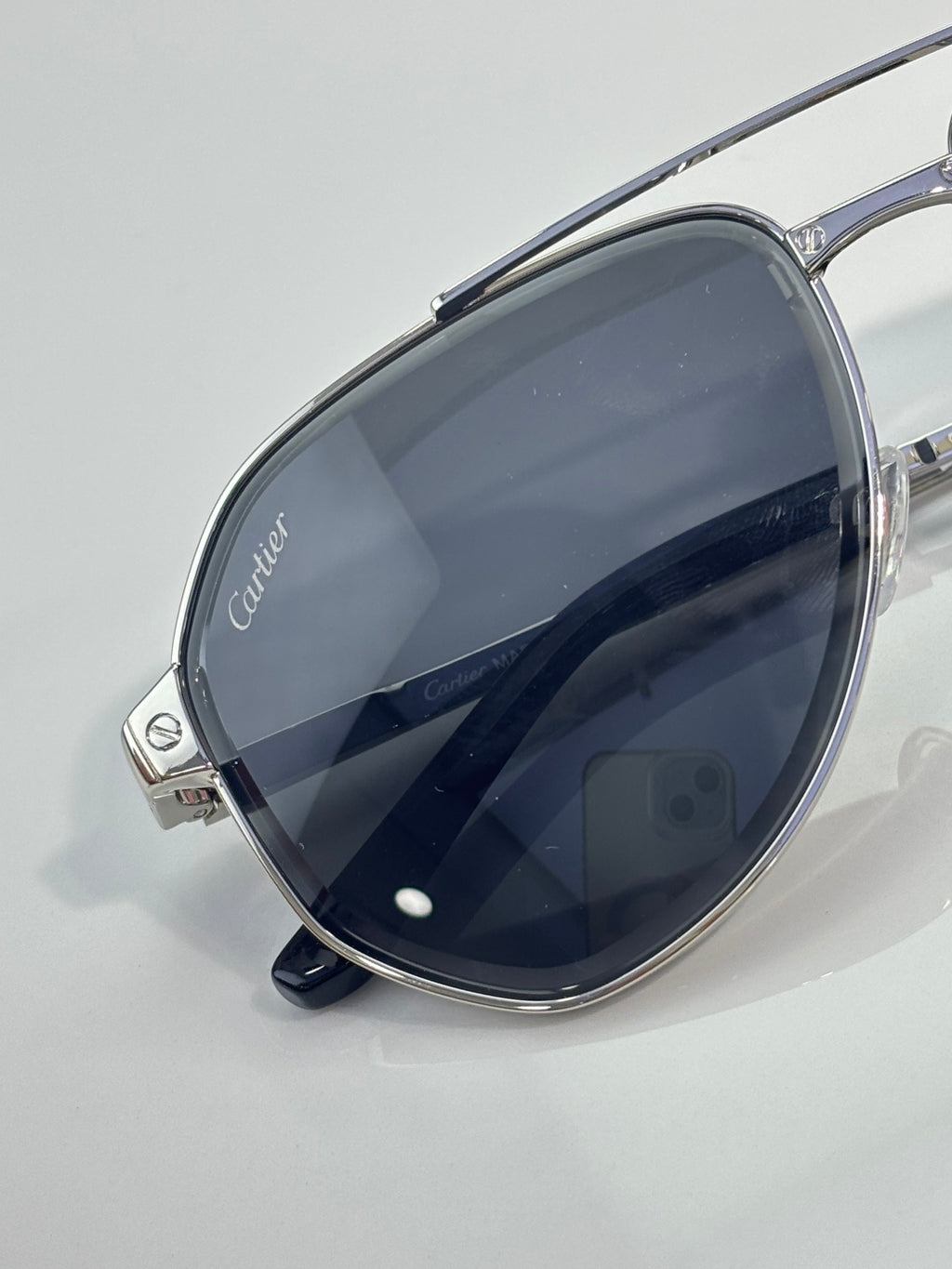 Cartier sunglasses close-up with dark navy-tinted lenses on silver metal frame