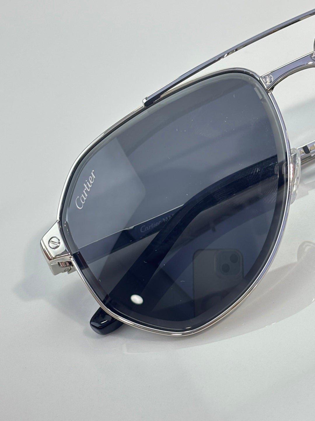 Cartier sunglasses close-up with dark navy-tinted lenses on silver metal frame