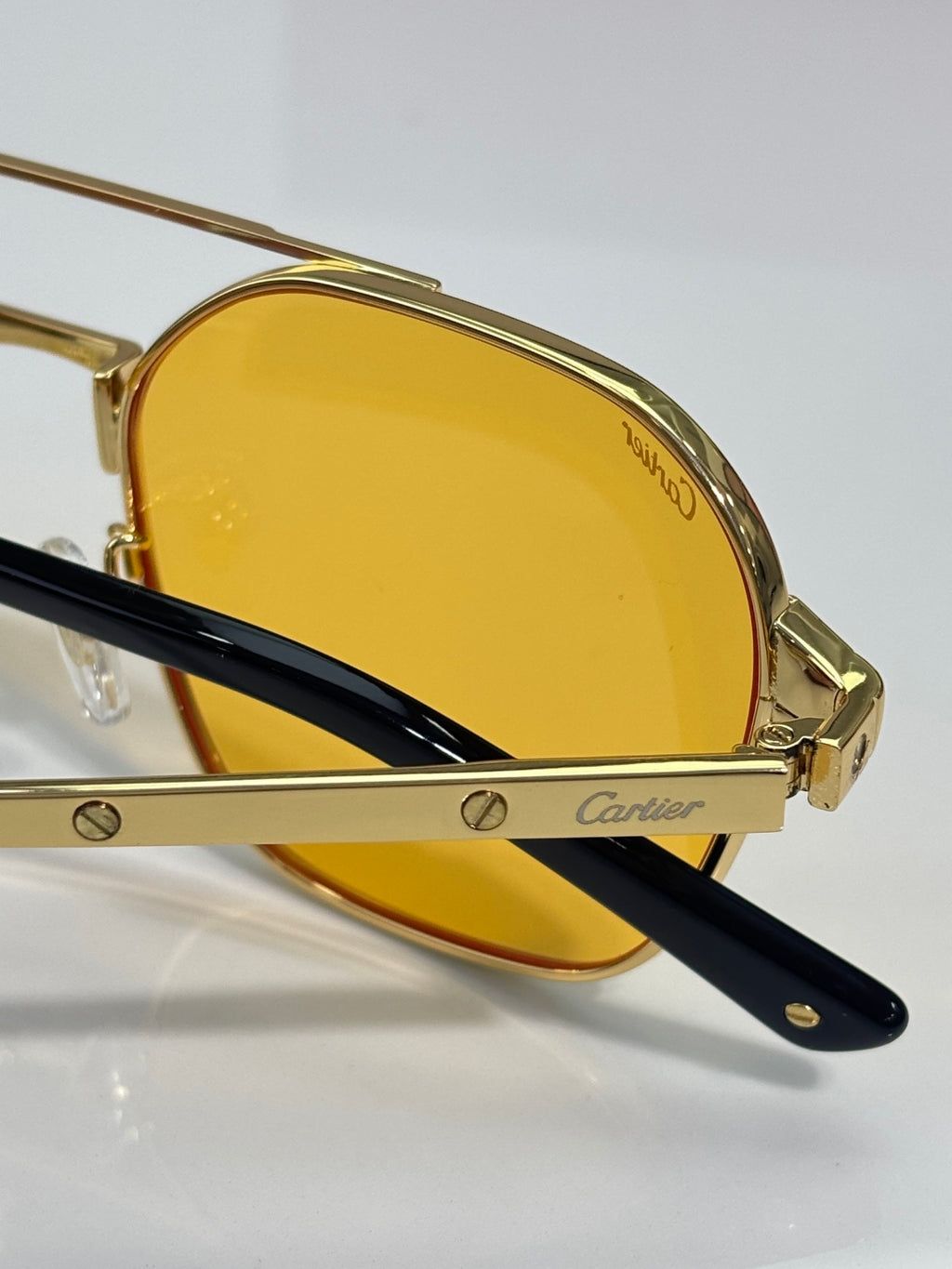 Side view of gold-tone sunglasses with amber lenses and black temple