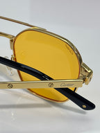 Side view of gold-tone sunglasses with amber lenses and black temple