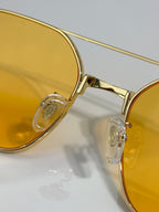 Close-up of gold-tone sunglasses frame with amber-tinted lenses