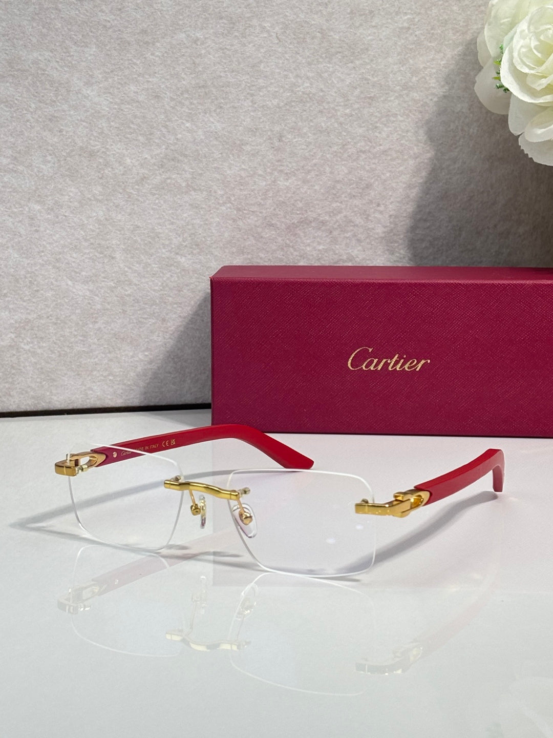 Eyeglasses with clear lenses, gold metal frame, red arms and gold-toned details