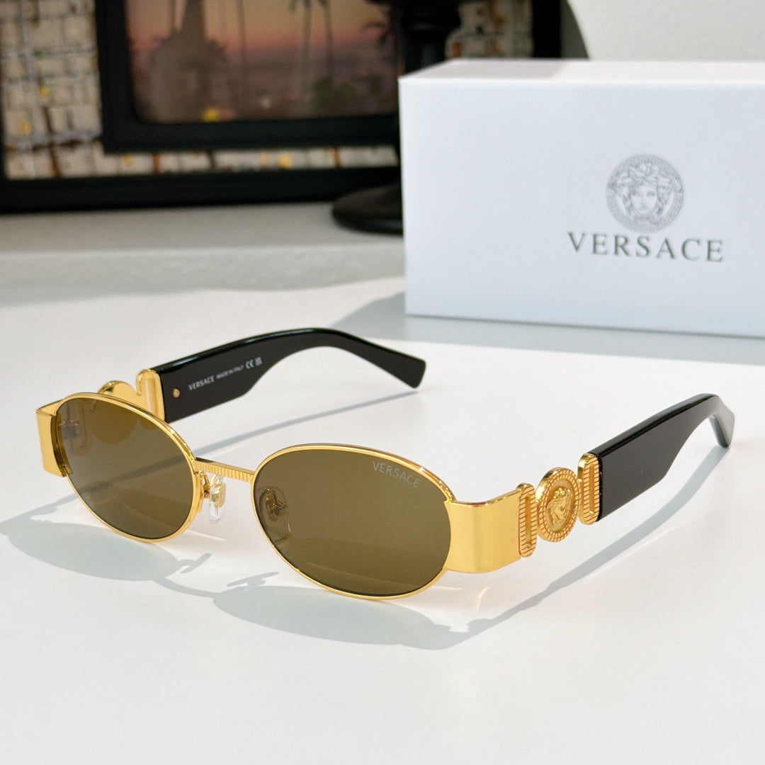 Versace sunglasses: gold frame, dark oval lenses, ornate temple accents.