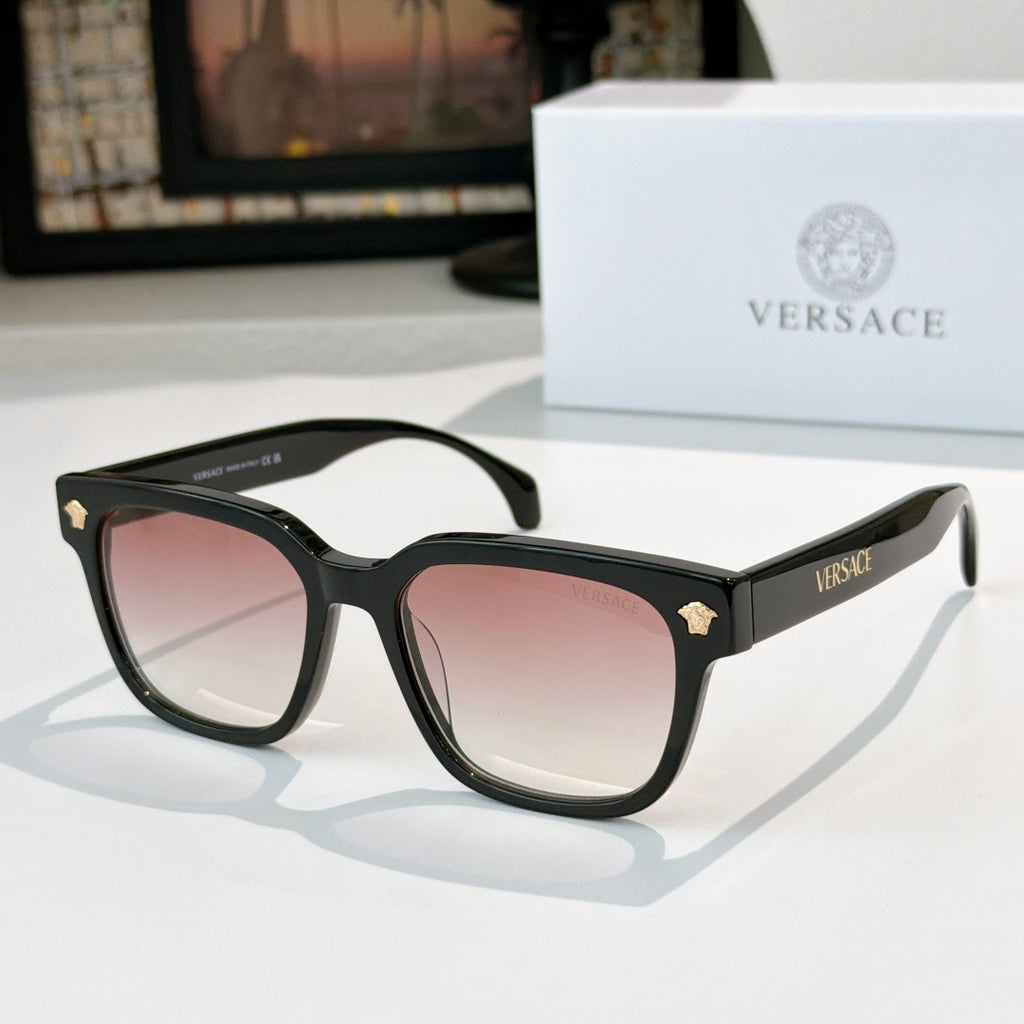 Black cat-eye sunglasses with pink tinted lenses and gold logo accents
