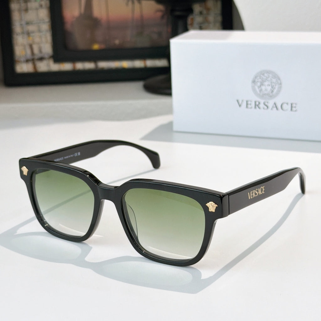 Black cat-eye sunglasses with green tinted lenses and gold logo accents