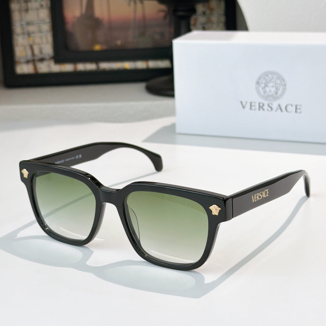 Black cat-eye sunglasses with green tinted lenses and gold logo accents