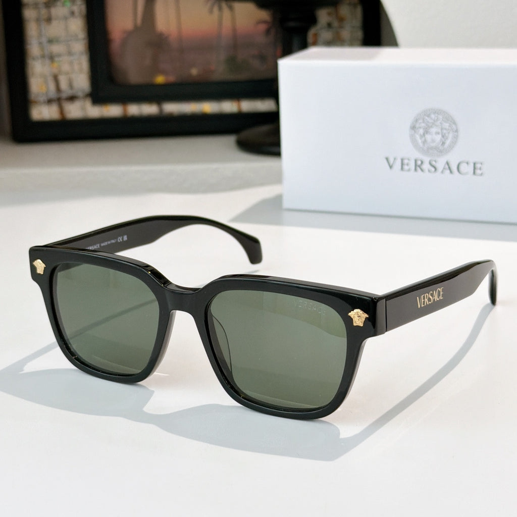 Black sunglasses with green tinted lenses and gold logo hinge details