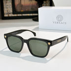 Black sunglasses with green tinted lenses and gold logo hinge details