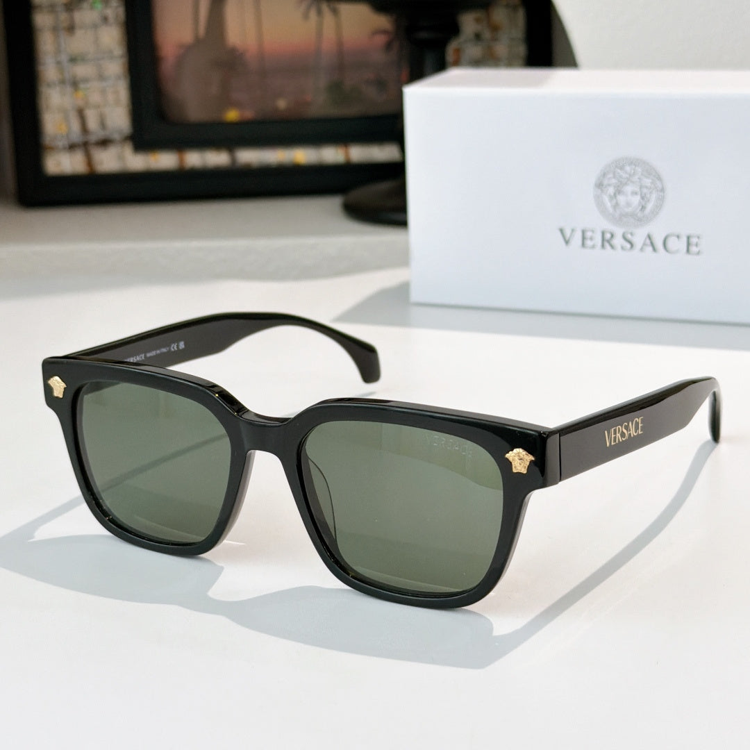 Black sunglasses with green tinted lenses and gold logo hinge details