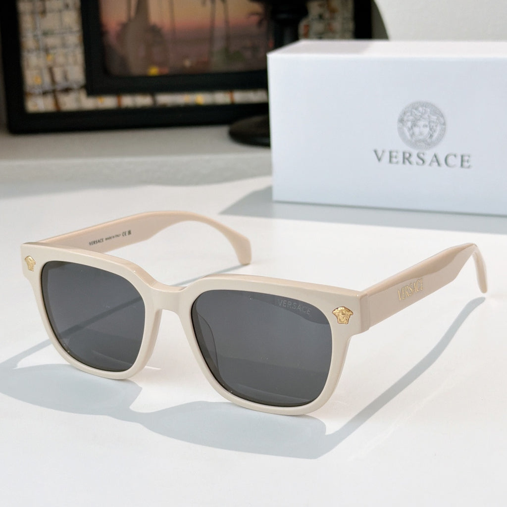Cream sunglasses with dark gray lenses and gold logo hinge details