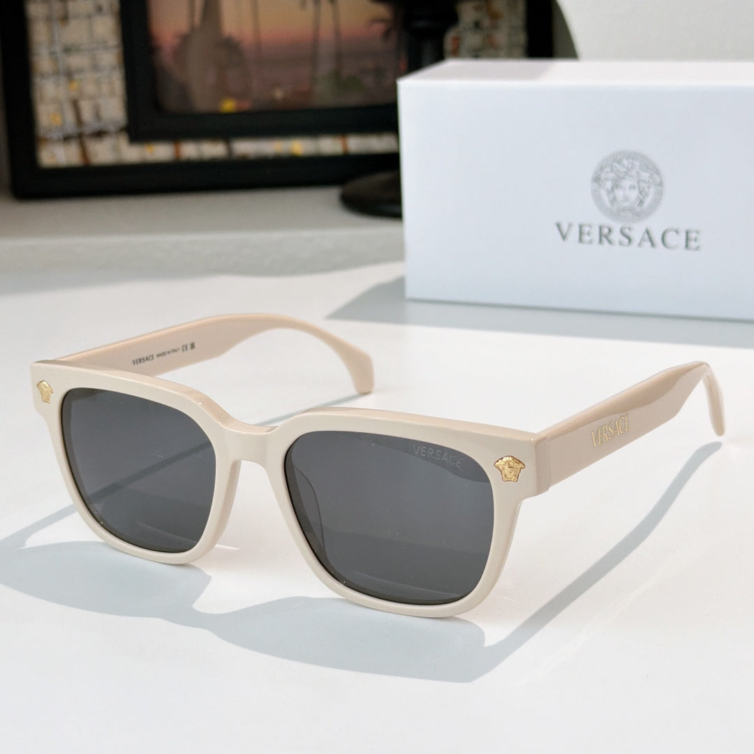Cream sunglasses with dark gray lenses and gold logo hinge details
